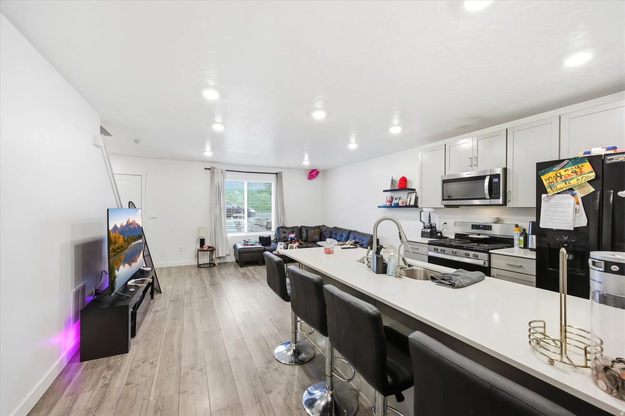 Open-concept living space featuring wood-finish flooring, recessed lighting, and a kitchen with light-toned cabinetry