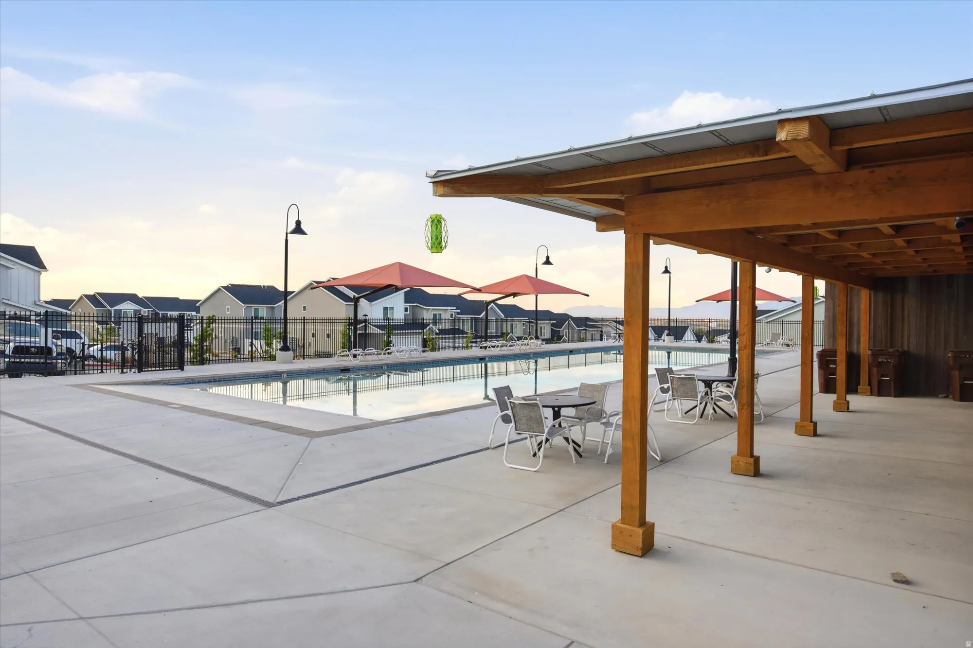 Expansive outdoor area featuring a swimming pool, concrete decking, and a covered patio structure with a metal roof