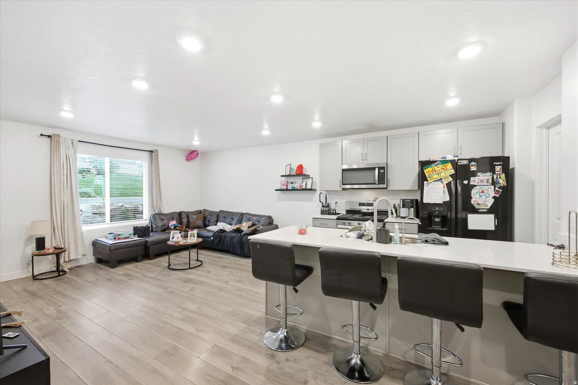 Open-concept living area featuring wood-finish flooring, recessed lighting, and a kitchen with light gray cabinetry