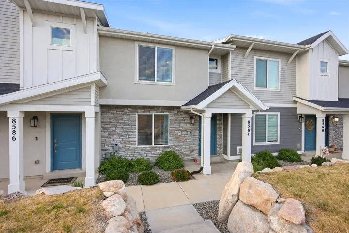 Contemporary multi-level townhome featuring a mix of horizontal siding, board-and-batten accents, and stone veneer detailing