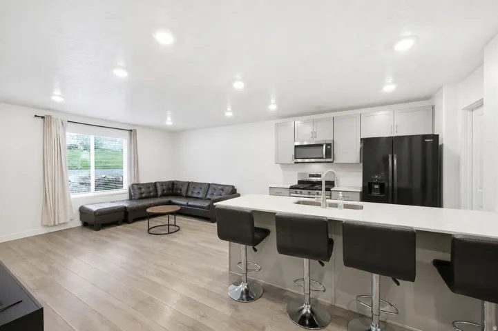 Open-concept living space featuring wood-finish flooring, recessed lighting, and a window with blinds