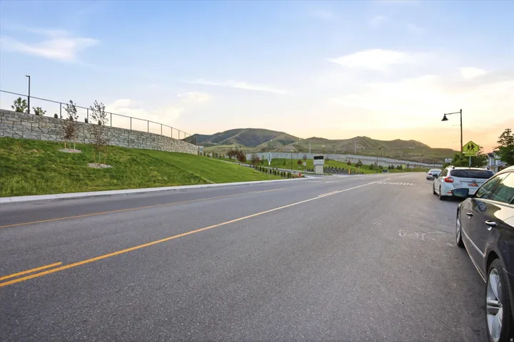 Paved street with striped lanes bordered by a manicured grassy slope