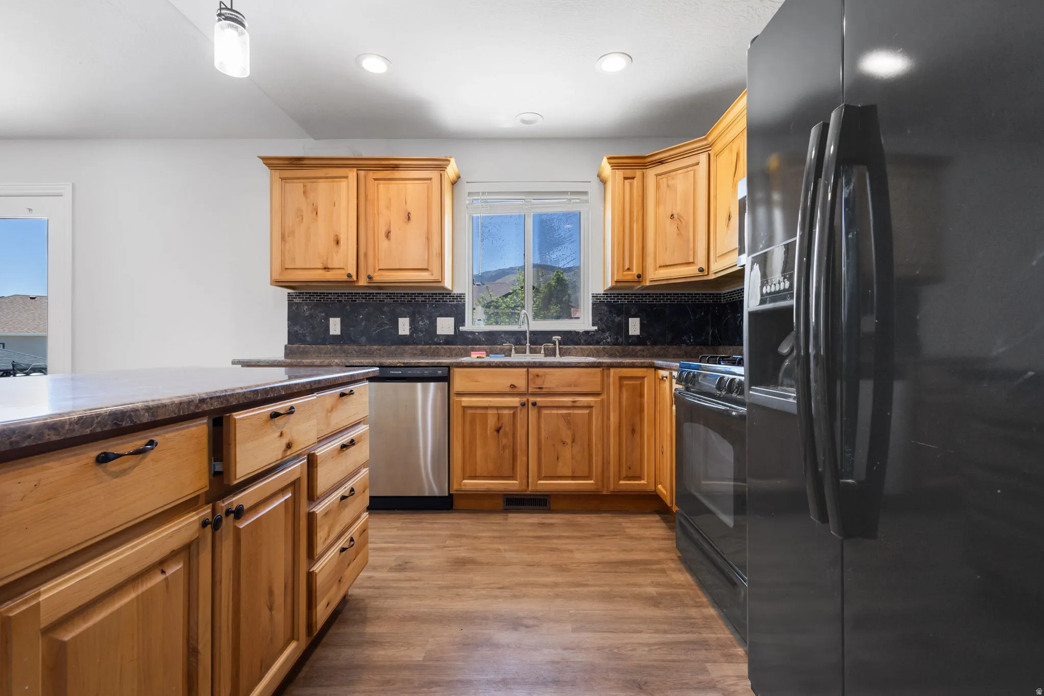 Kitchen featuring wood cabinetry, stone-look countertops, and a full suite of appliances