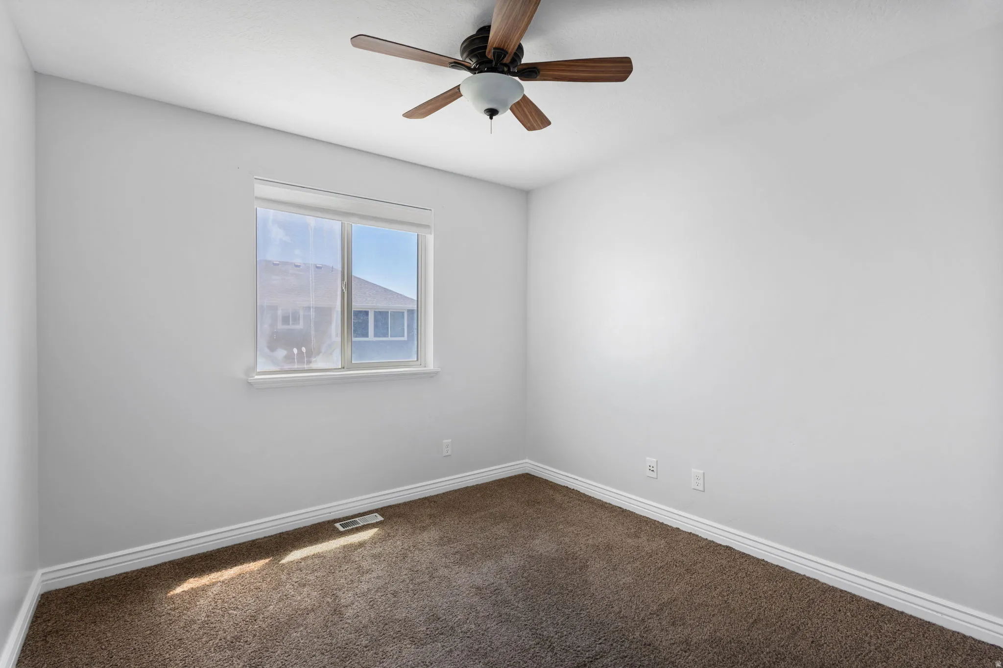 Bright room featuring a ceiling fan with wood-finish blades and integrated lighting, a double-pane window, and neutral-toned carpeting