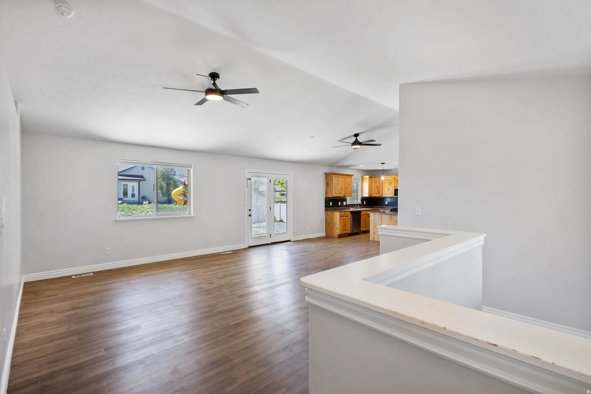 Vaulted ceilings with exposed beams and two ceiling fans, wood-finish flooring, and white walls