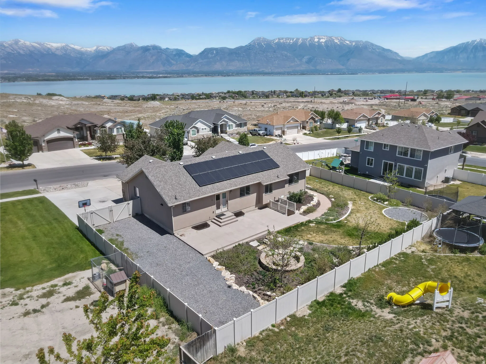 Single-story residence featuring solar panels, a concrete patio, and an extended gravel driveway