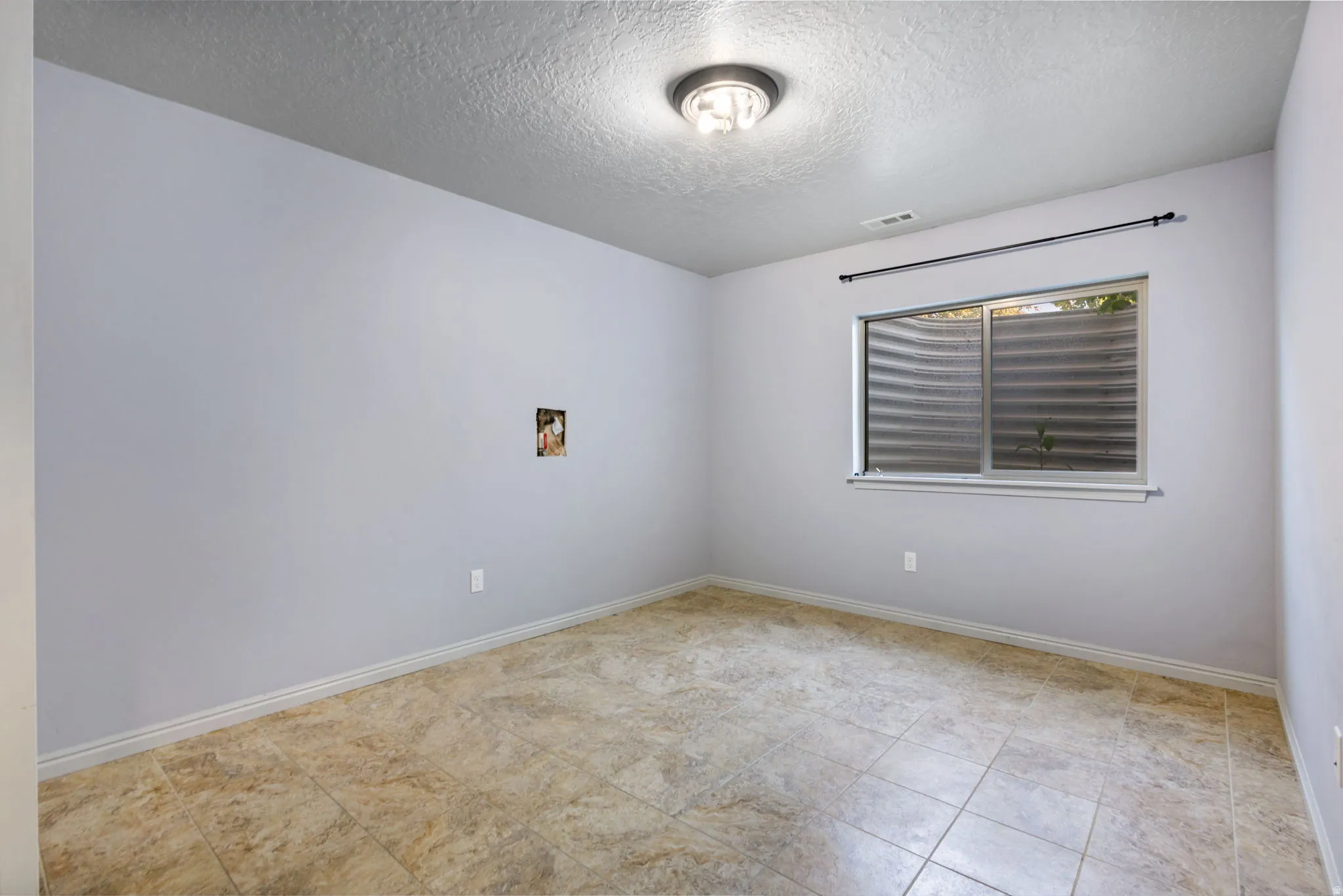 Room featuring light-colored walls and a window with a metal window well