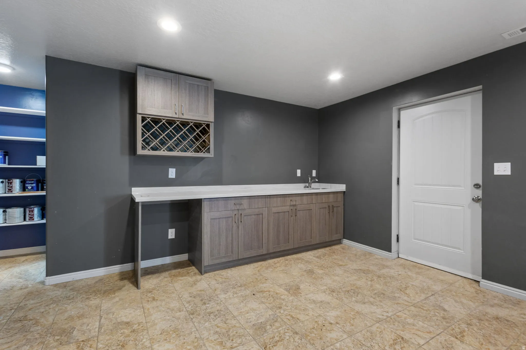 Wet bar featuring light wood-finish cabinetry, an integrated sink, and a built-in wine rack