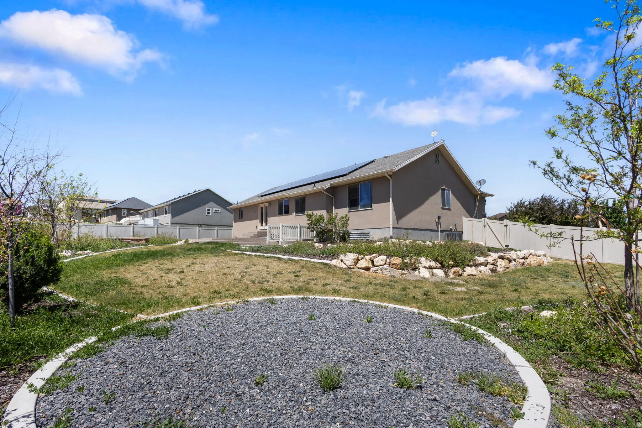 Expansive backyard featuring a terraced landscape, decorative gravel beds, and a full privacy fence