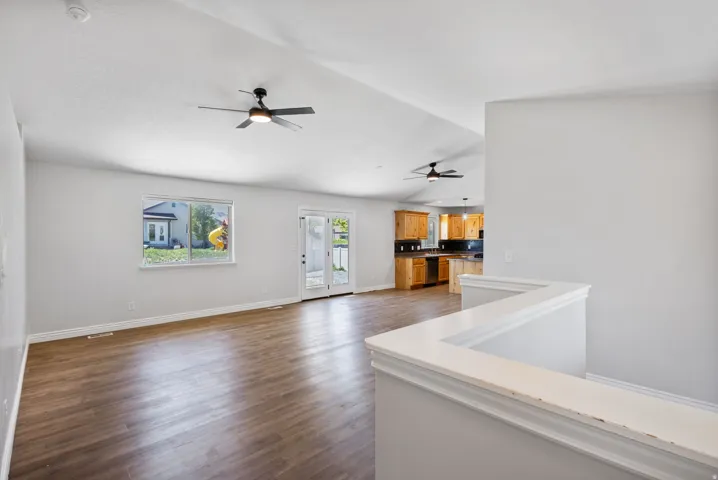 Vaulted ceilings with exposed beams and two ceiling fans, wood-finish flooring, and white walls