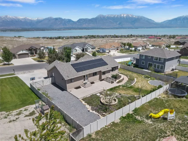 Single-story residence featuring solar panels, a concrete patio, and an extended gravel driveway