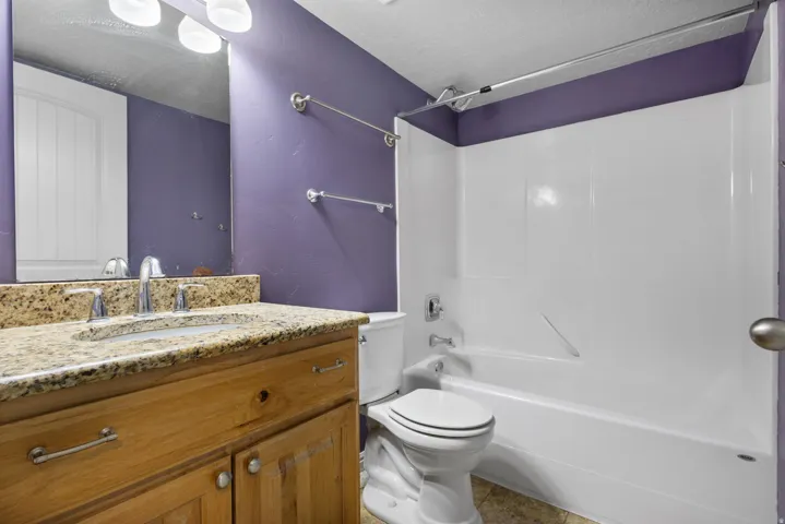 Bathroom vanity featuring a polished stone countertop, undermount sink, and chrome faucet