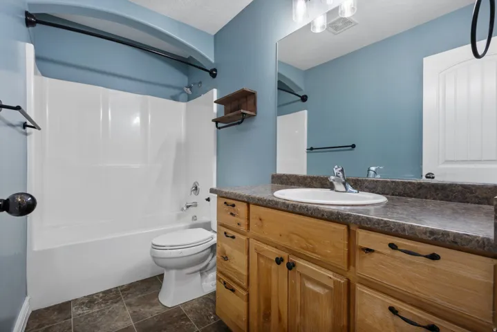 Bathroom featuring a vanity with wood-finish cabinetry, a single basin sink, and a large mirror