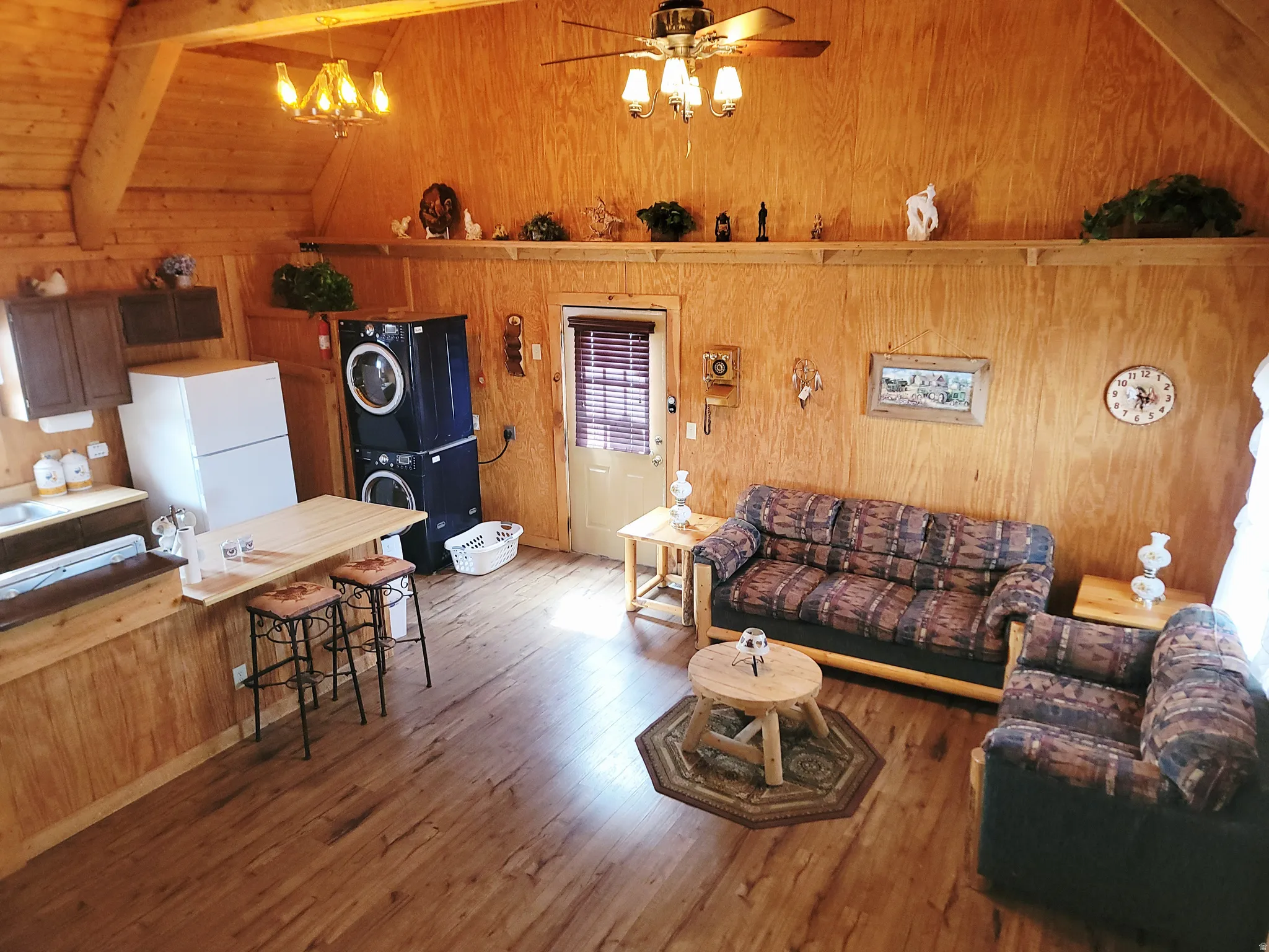 Open-concept living space featuring wood-finish flooring, wood paneling, and a vaulted ceiling with exposed beams