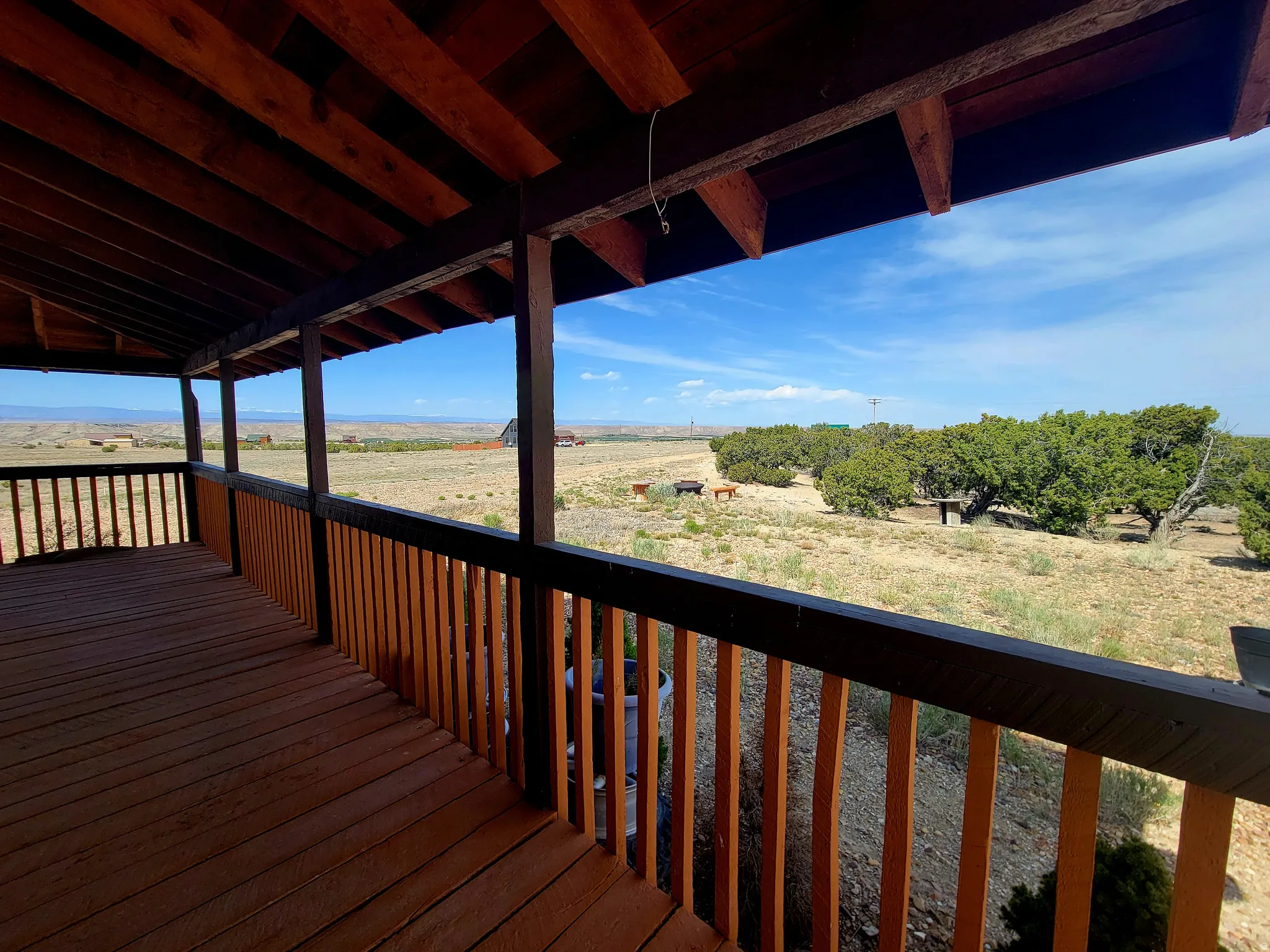 Covered wood deck with rich wood-tone flooring and railings, offering expansive outdoor space