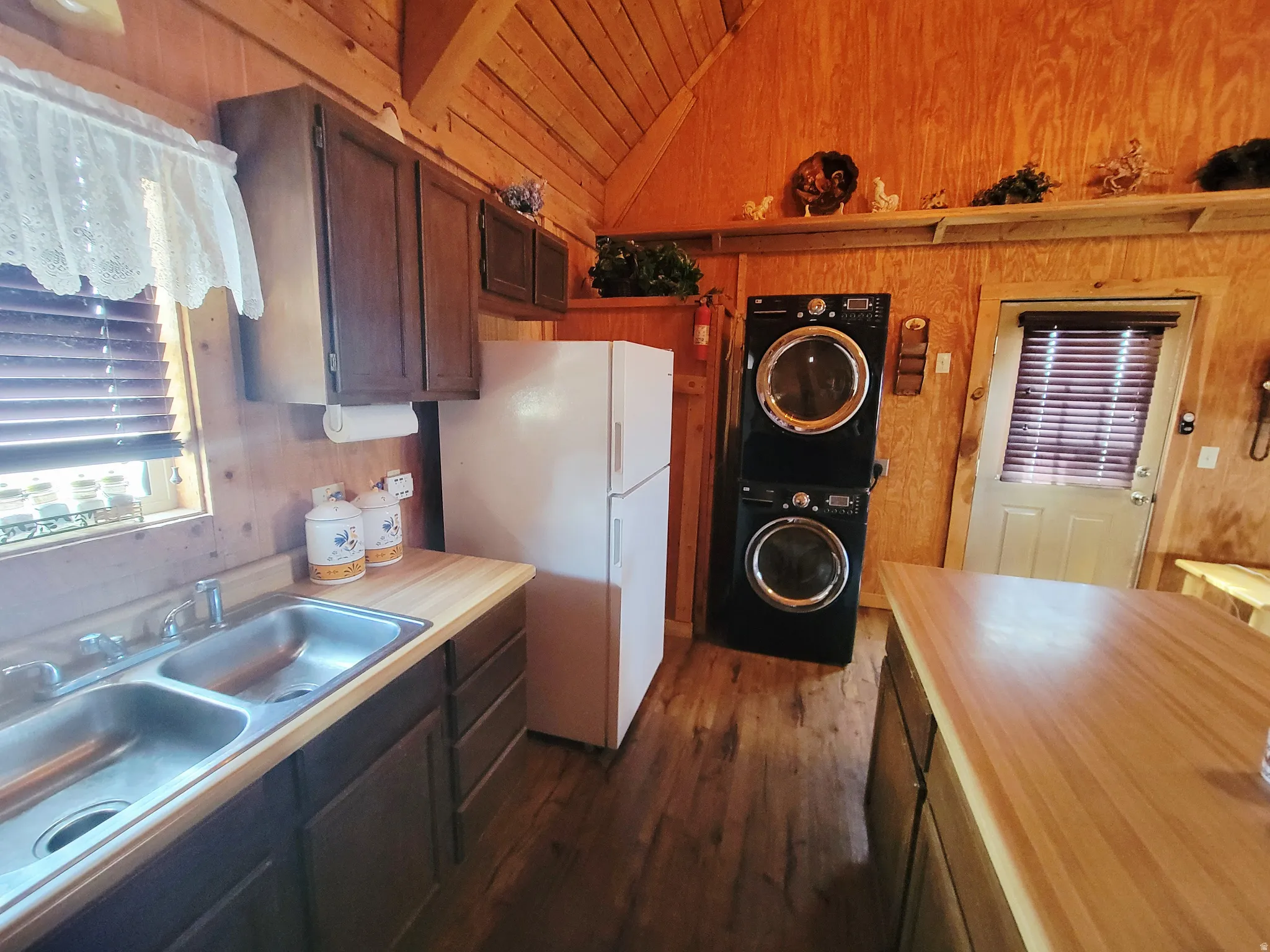 Kitchen area featuring wood-finish flooring, light wood countertops, dark wood cabinetry, and a double basin stainless steel sink