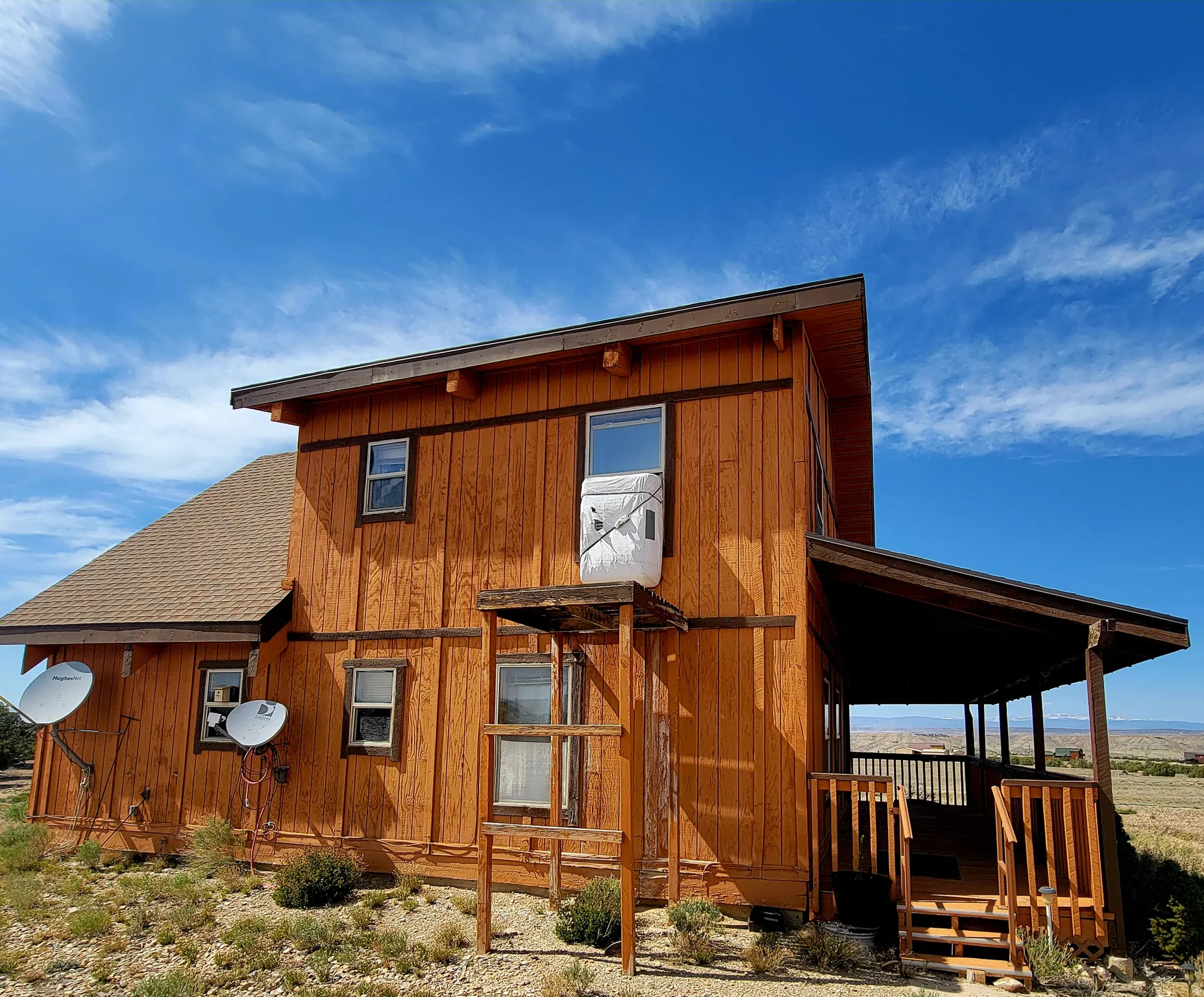 Wood-sided exterior featuring multiple windows and a covered porch with wood railings
