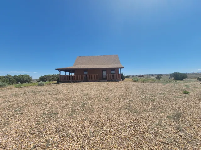 Wood-sided cabin-style residence featuring a covered front porch, exposed wood railing, and a shingled roof