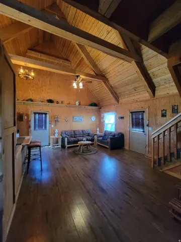 Spacious interior featuring exposed beam ceilings, wood-finish flooring, and wood paneling throughout