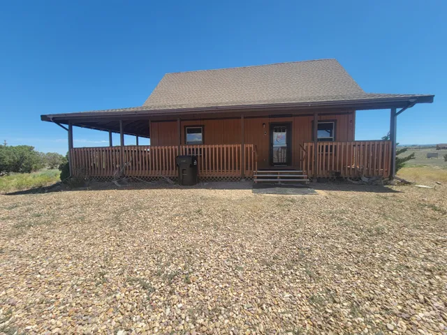 Cabin-style residence featuring a broad covered front porch, wood siding, and a gabled roof