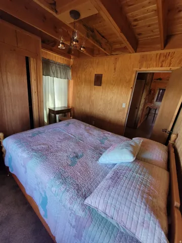 Interior room featuring wood-finish walls, exposed wood-finish ceiling beams, and a built-in ceiling light fixture