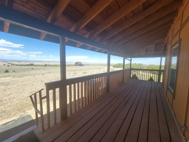 Expansive covered porch featuring wood-finish flooring, a wood railing, and exposed wood ceiling beams