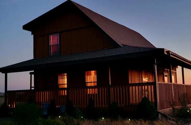 Two-story residence featuring a covered front porch with wood railings and a dark shingle roof