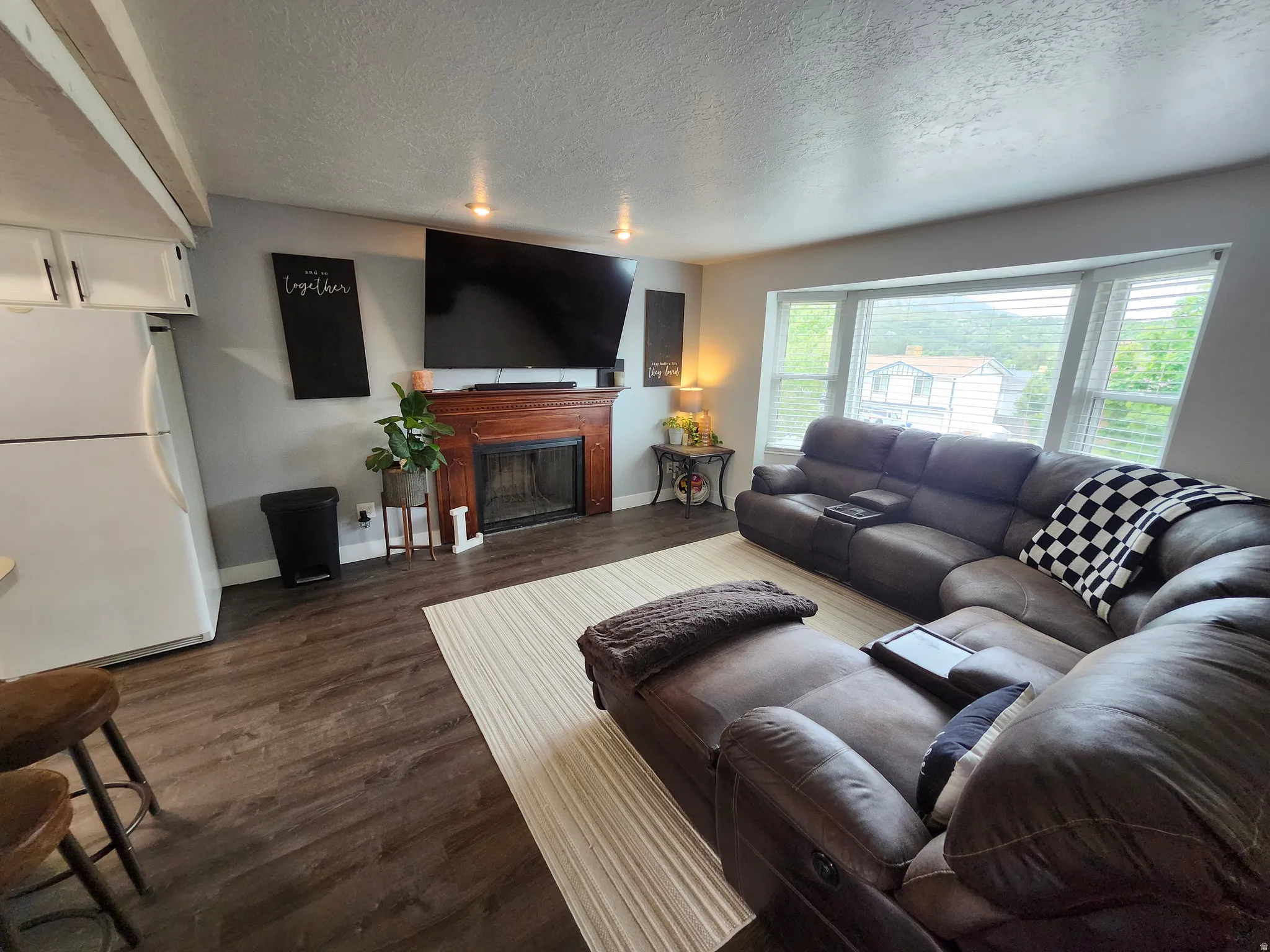 Spacious living area featuring LVP flooring, a traditional fireplace with a wooden mantel, and recessed lighting