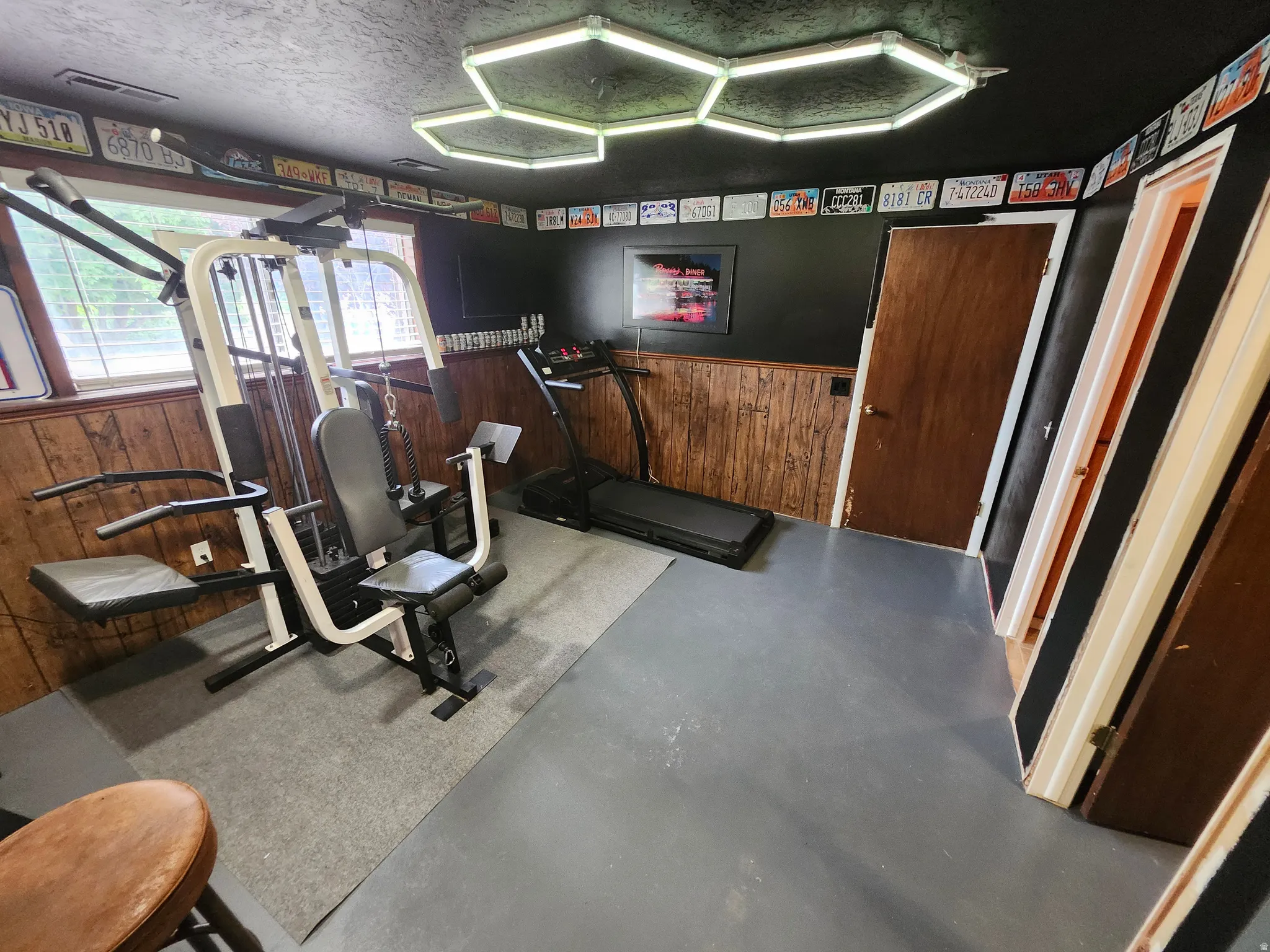 Dedicated room featuring wood paneling, multiple doorways, and overhead geometric lighting