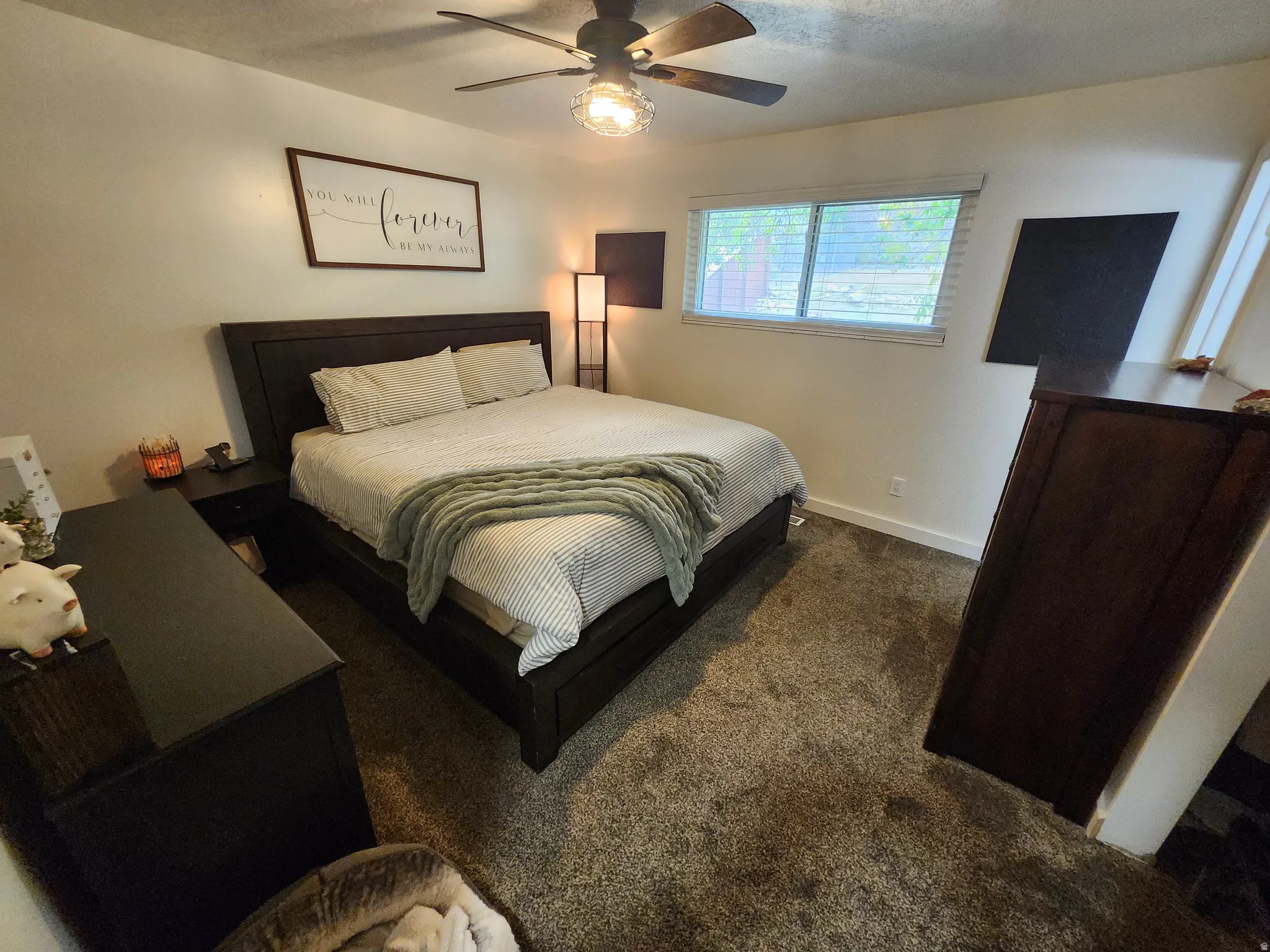 Carpeted room featuring a ceiling fan with light fixture, window with blinds, and white baseboards