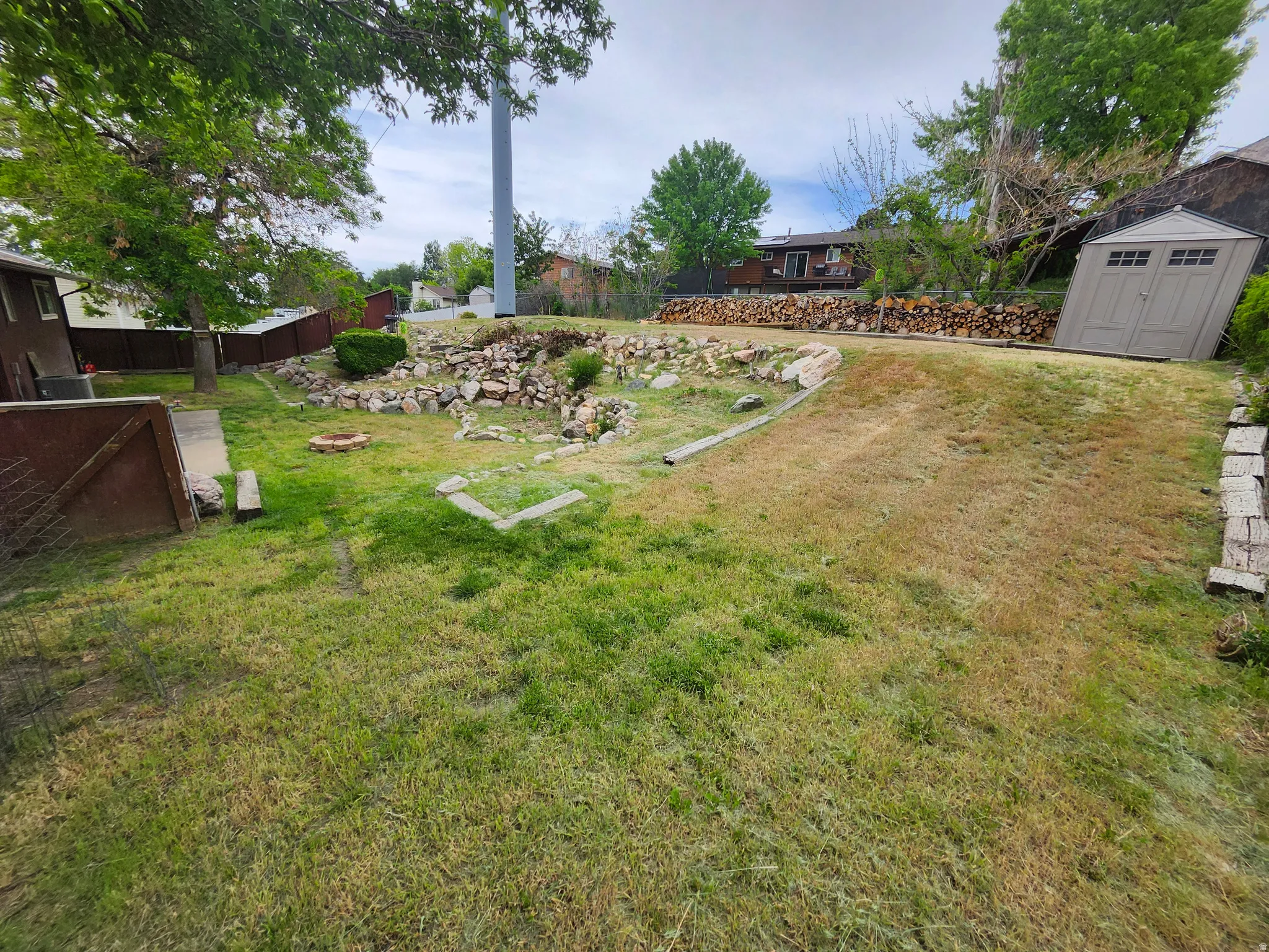 Expansive backyard featuring a combination of grassy areas and a rock garden