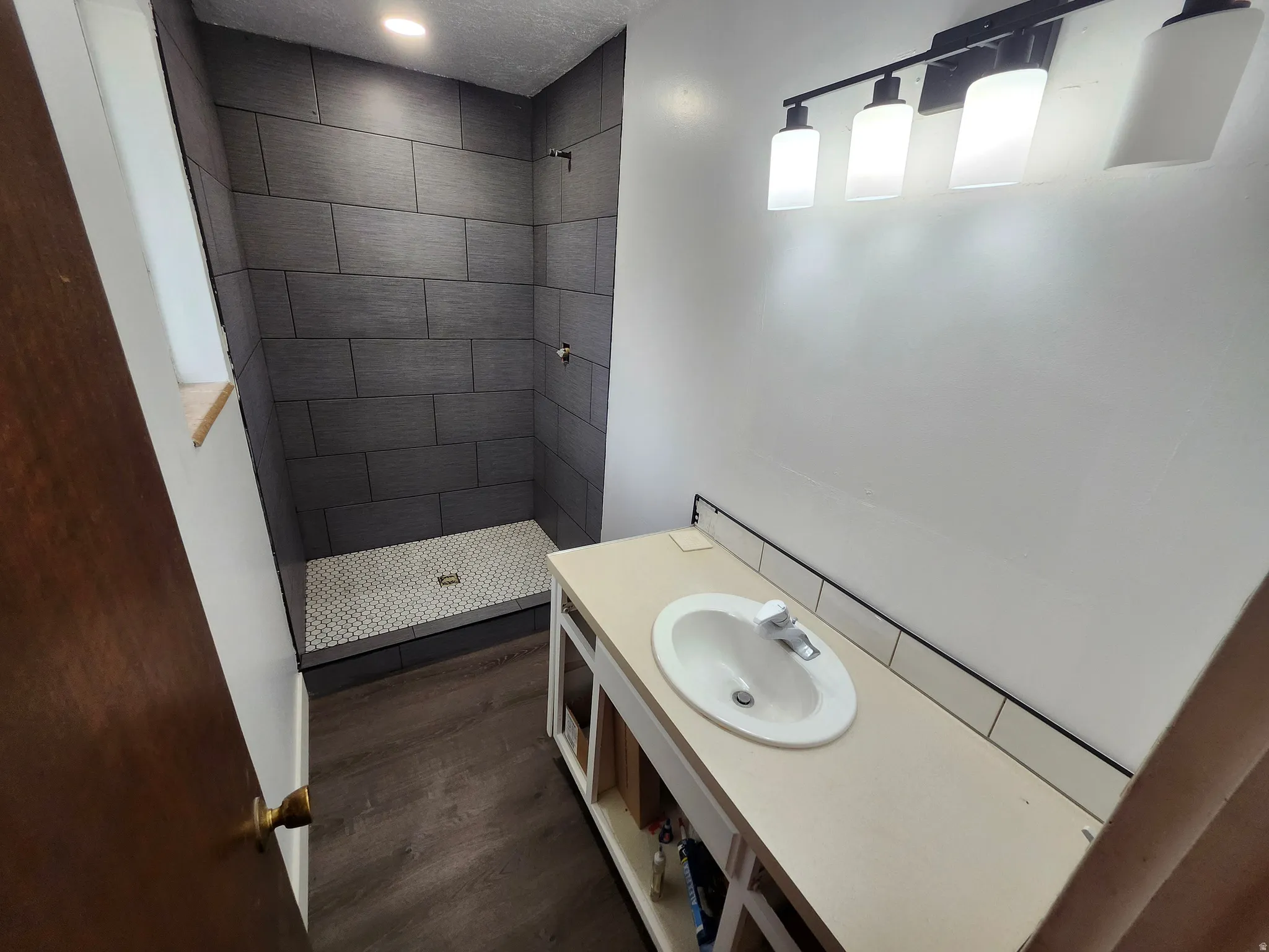 Bathroom featuring a walk-in shower with dark gray rectangular tile and white penny round mosaic flooring