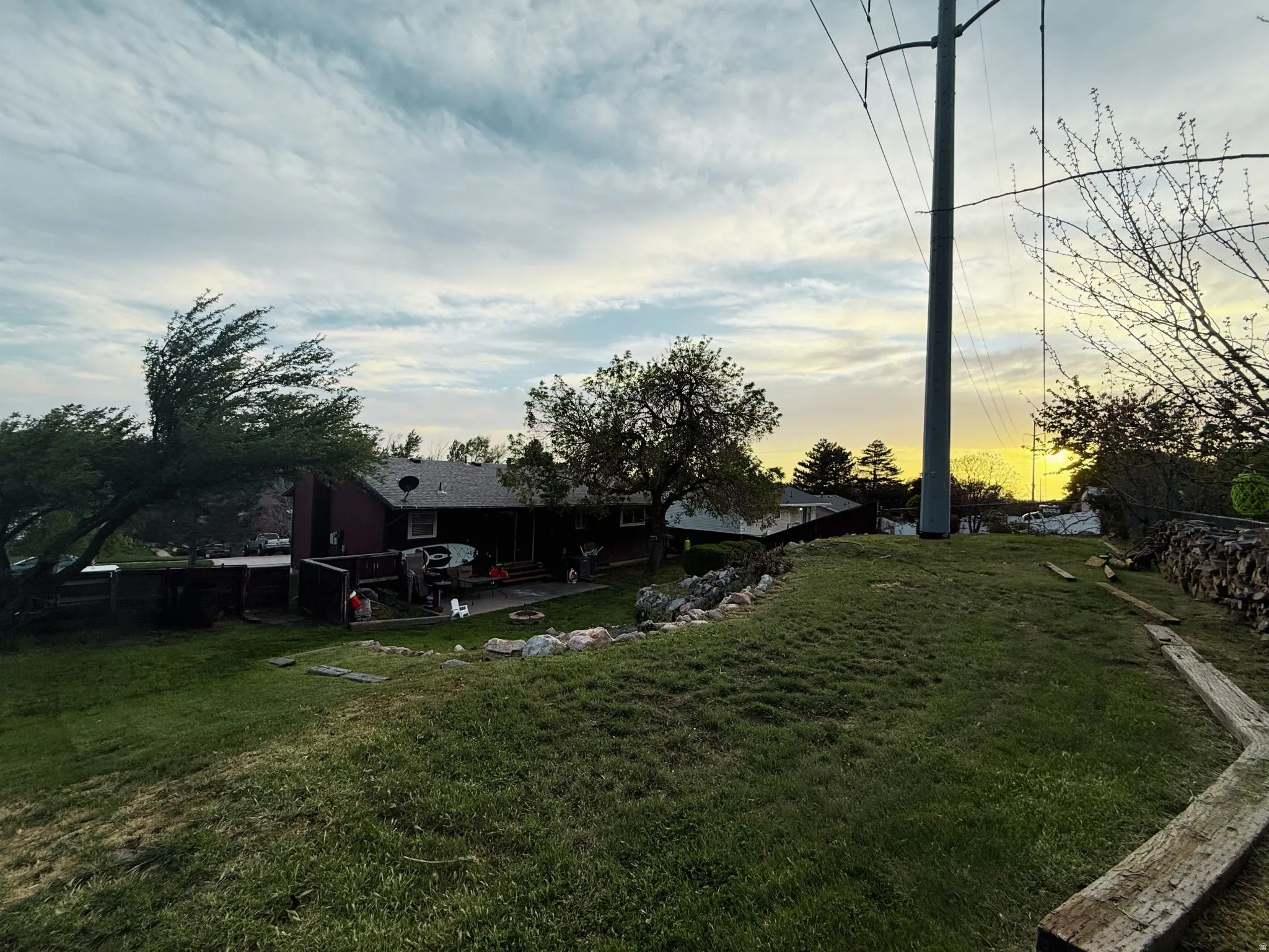 Expansive sloped lawn area features established trees and a stone retaining wall