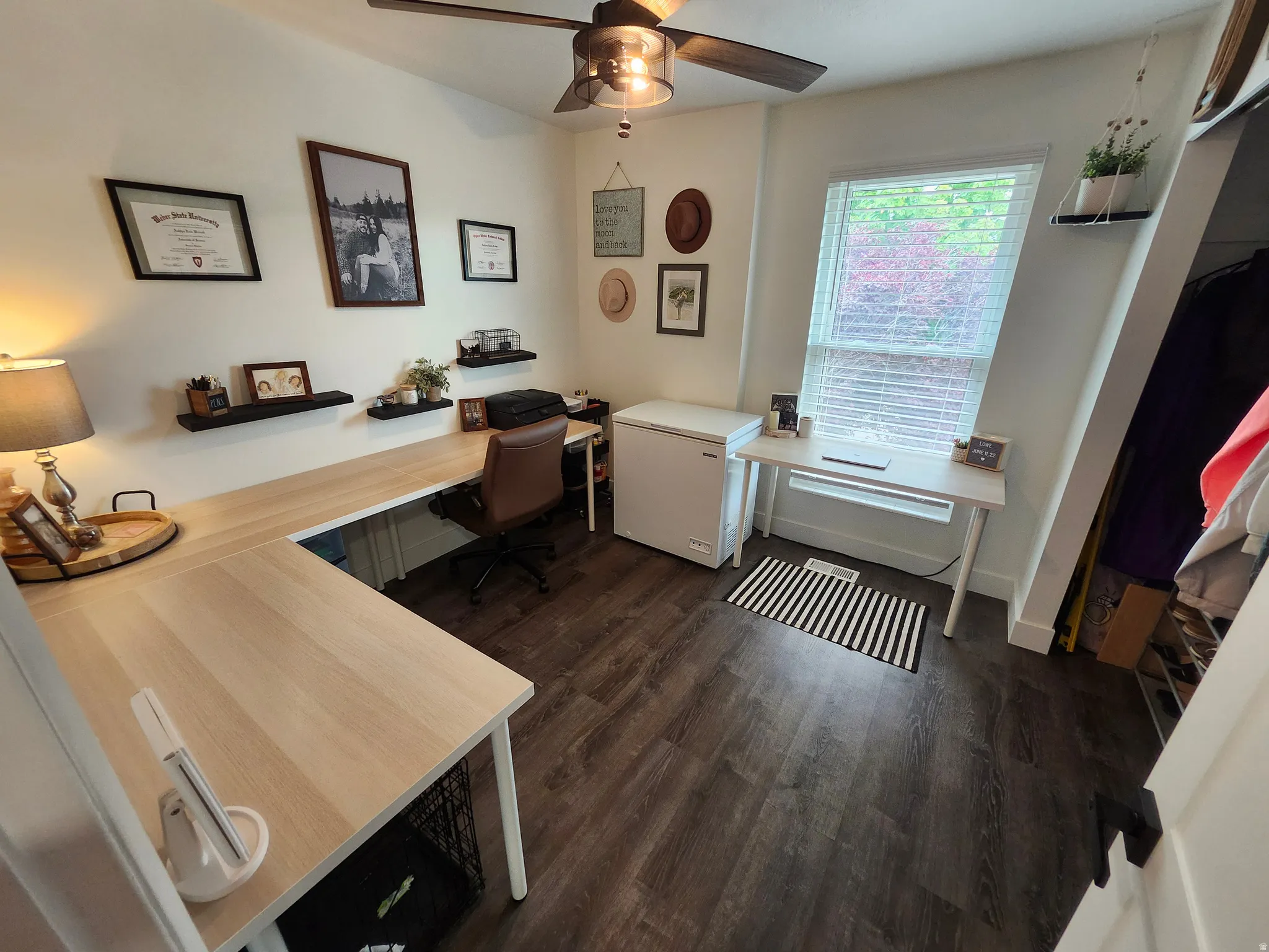 Versatile interior space featuring wood-finish flooring, white walls, and a ceiling fan with integrated lighting