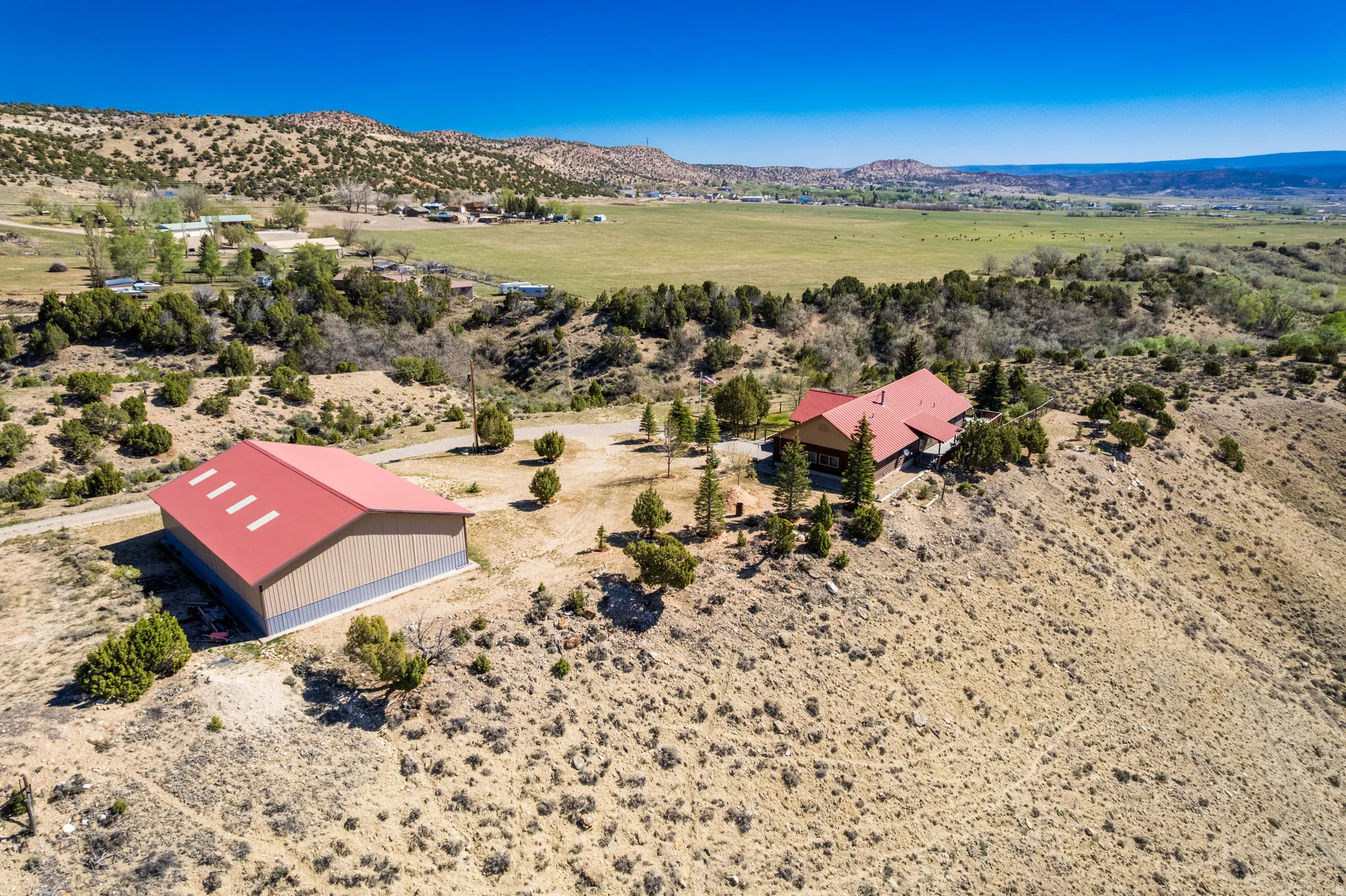 Expansive property featuring a residence and a separate large outbuilding, both with red metal roofs