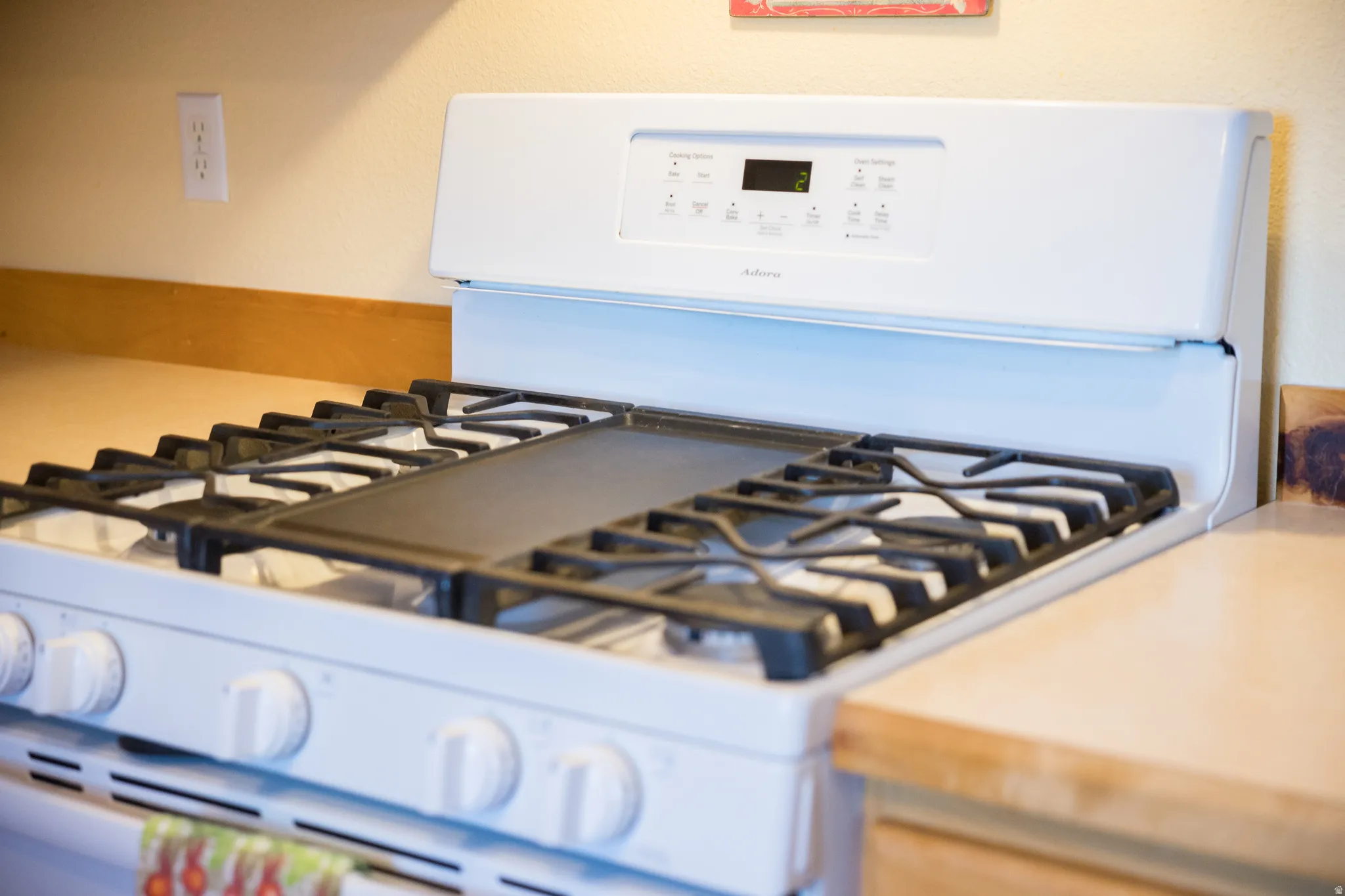 White gas range with a black griddle insert and cast-iron grates
