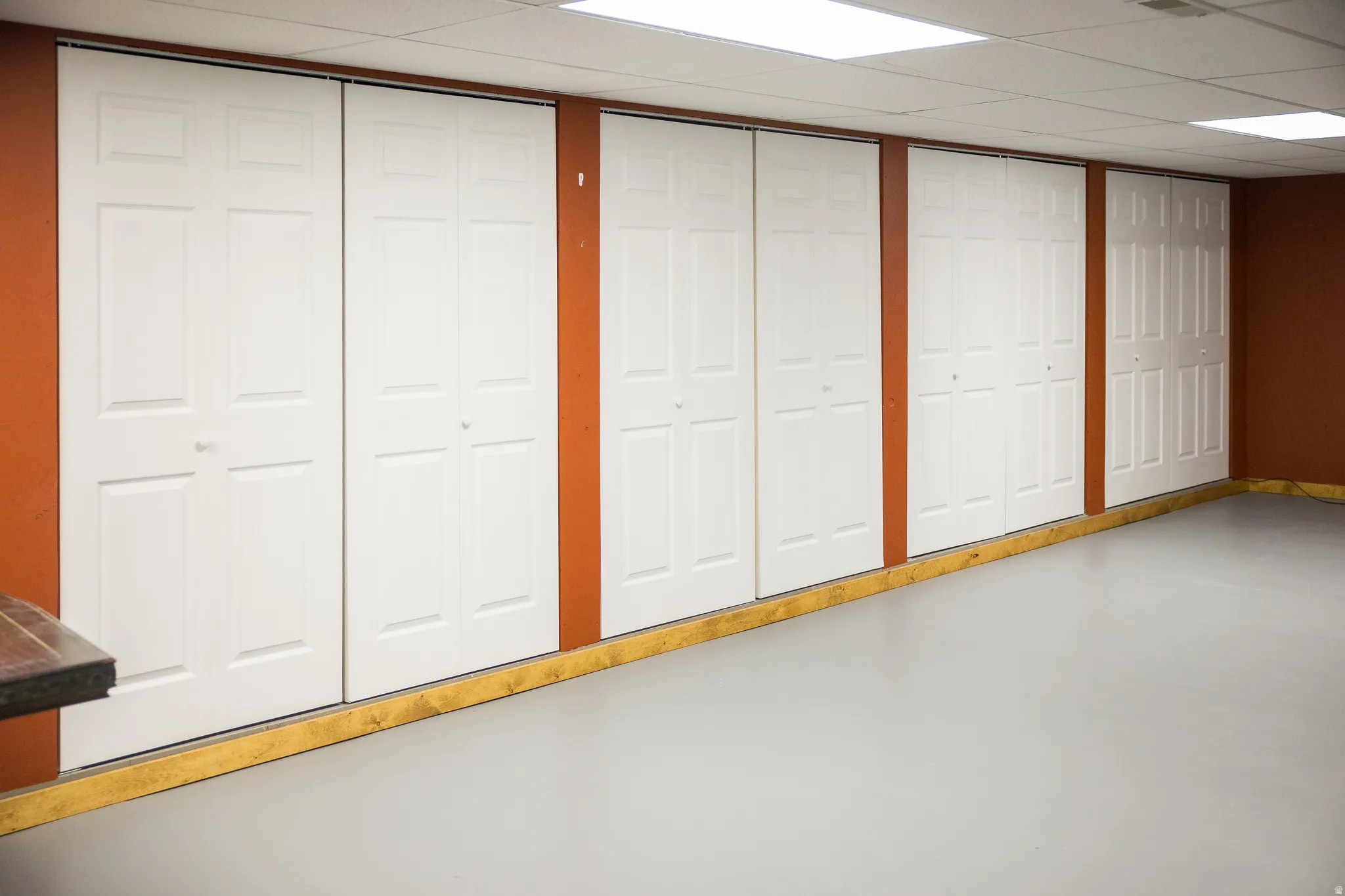 Wall-length white bi-fold doors offering extensive storage against a warm-toned wall