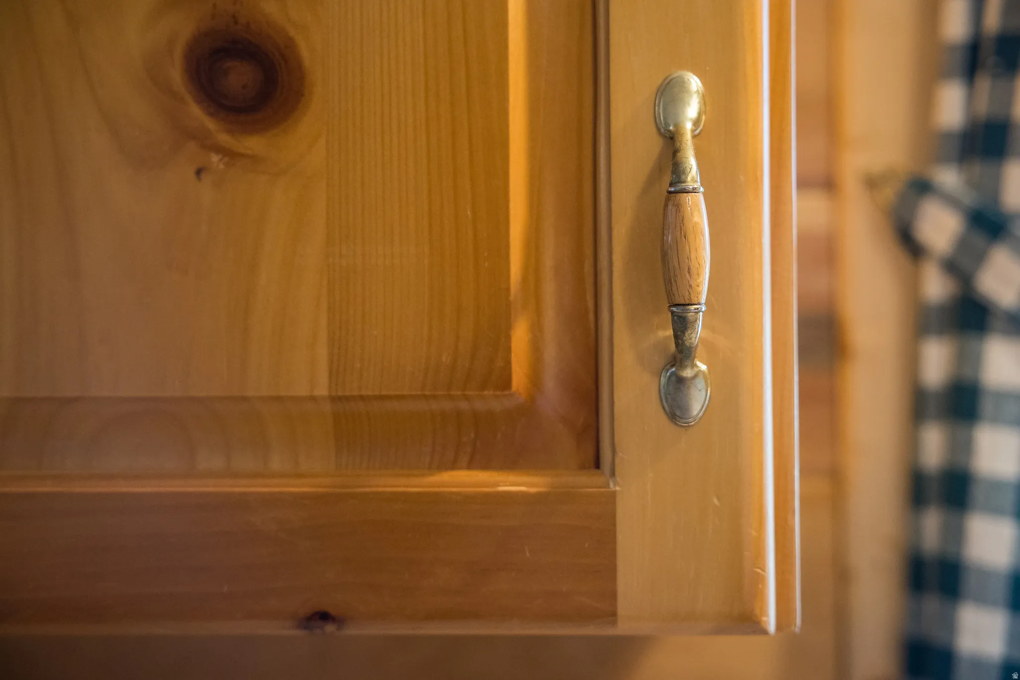 Light wood-finish cabinetry featuring prominent wood grain and a decorative metal and wood pull handle