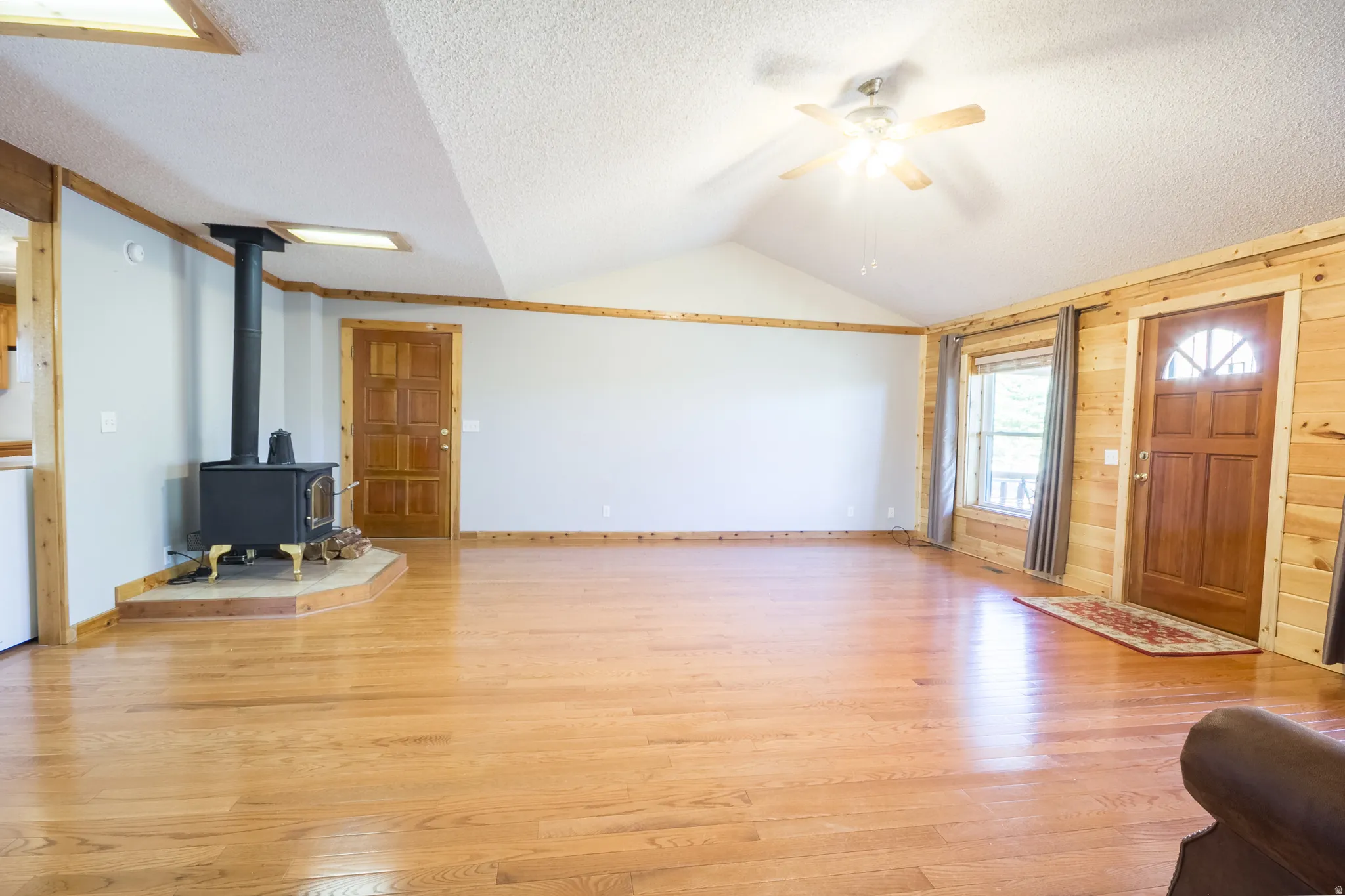 Expansive living area featuring wood-finish flooring, a vaulted ceiling, and a ceiling fan