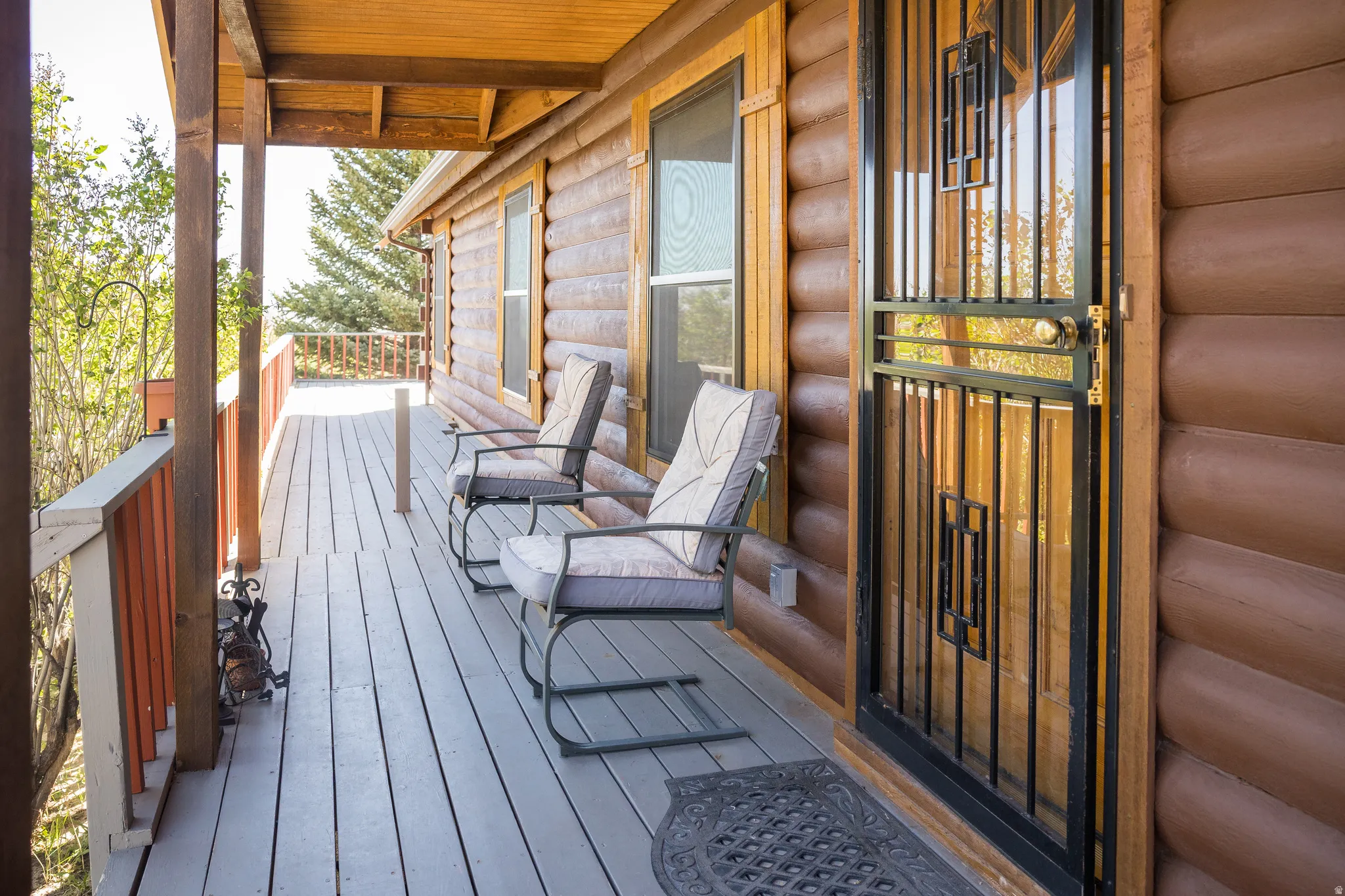Expansive wooden deck with a log cabin exterior and decorative security screen door
