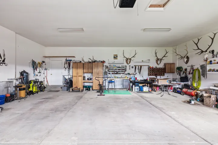 Spacious garage featuring concrete flooring, built-in wooden cabinetry, ample wall storage, and overhead fluorescent lighting