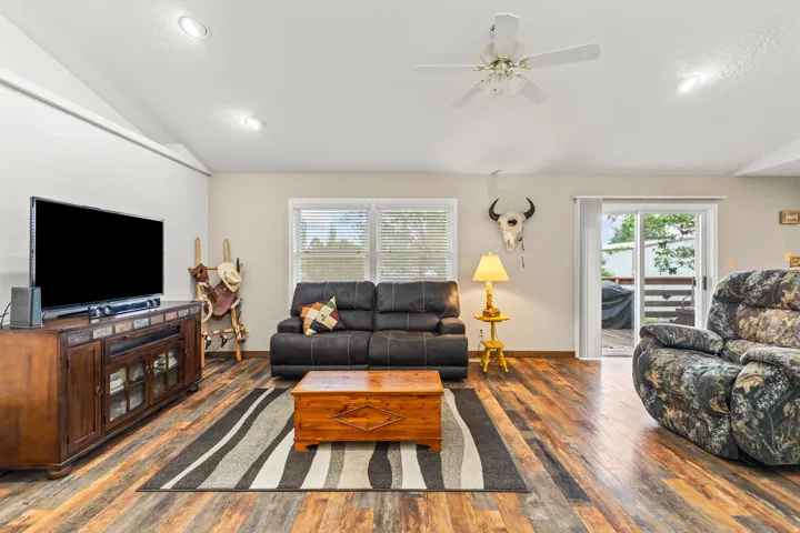Spacious living area featuring wood-finish flooring, a vaulted ceiling, and recessed lighting