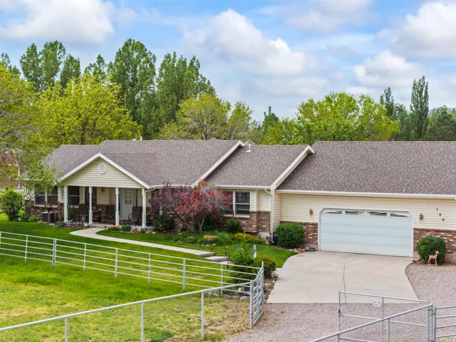 Ranch-style residence featuring a covered front porch with white columns, a two-car garage, and a concrete driveway