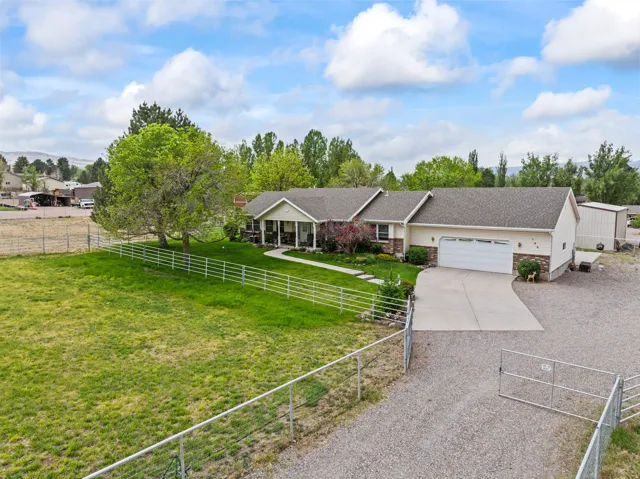 Ranch-style residence featuring a stone and siding exterior, an attached two-car garage, a gravel driveway, and a separate outbuilding