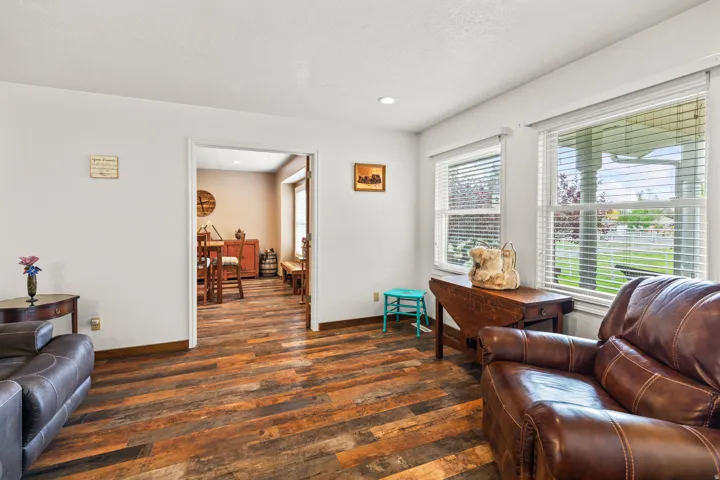 Spacious interior featuring wood-finish flooring, white walls, and multiple windows with horizontal blinds