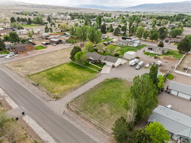 Aerial perspective showcasing a residential property with a ranch-style home, attached garage, and multiple outbuildings