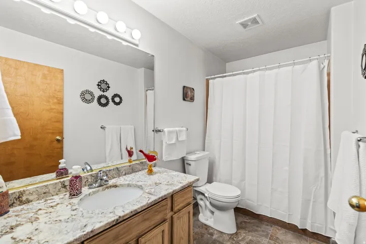 Bathroom featuring a vanity with a light-toned stone countertop, an integrated sink, and wood-finish cabinetry