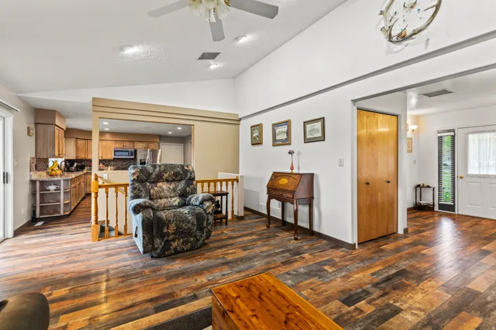 Spacious living area featuring wood-finish flooring, vaulted ceilings, and recessed lighting