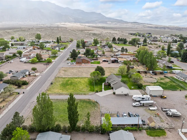 Aerial perspective showcasing a single-story residence with an attached garage, paved driveway, and dedicated gravel parking areas