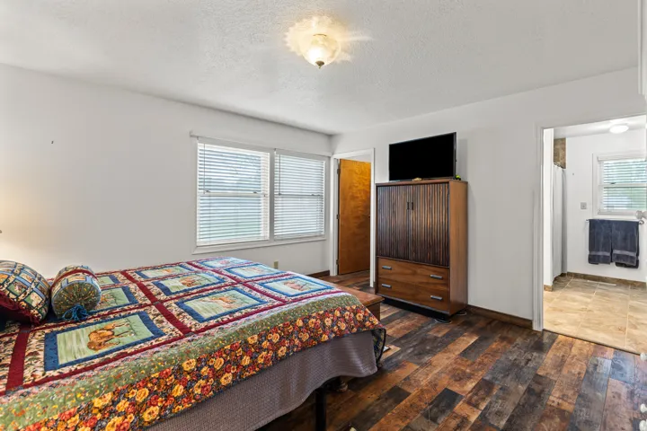 Spacious room featuring wood-finish flooring, white walls, and a ceiling light fixture